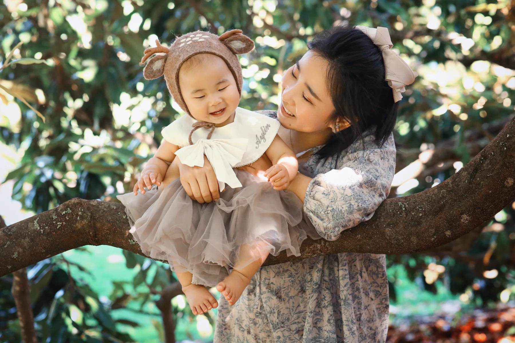 Mother holding her child under a tree